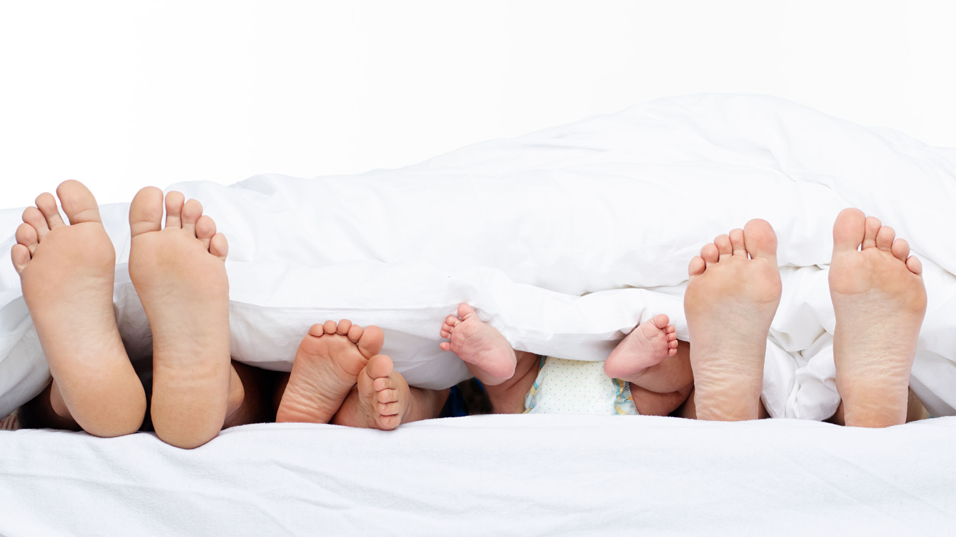 famiglia dorme con piedi fuori dalle coperte