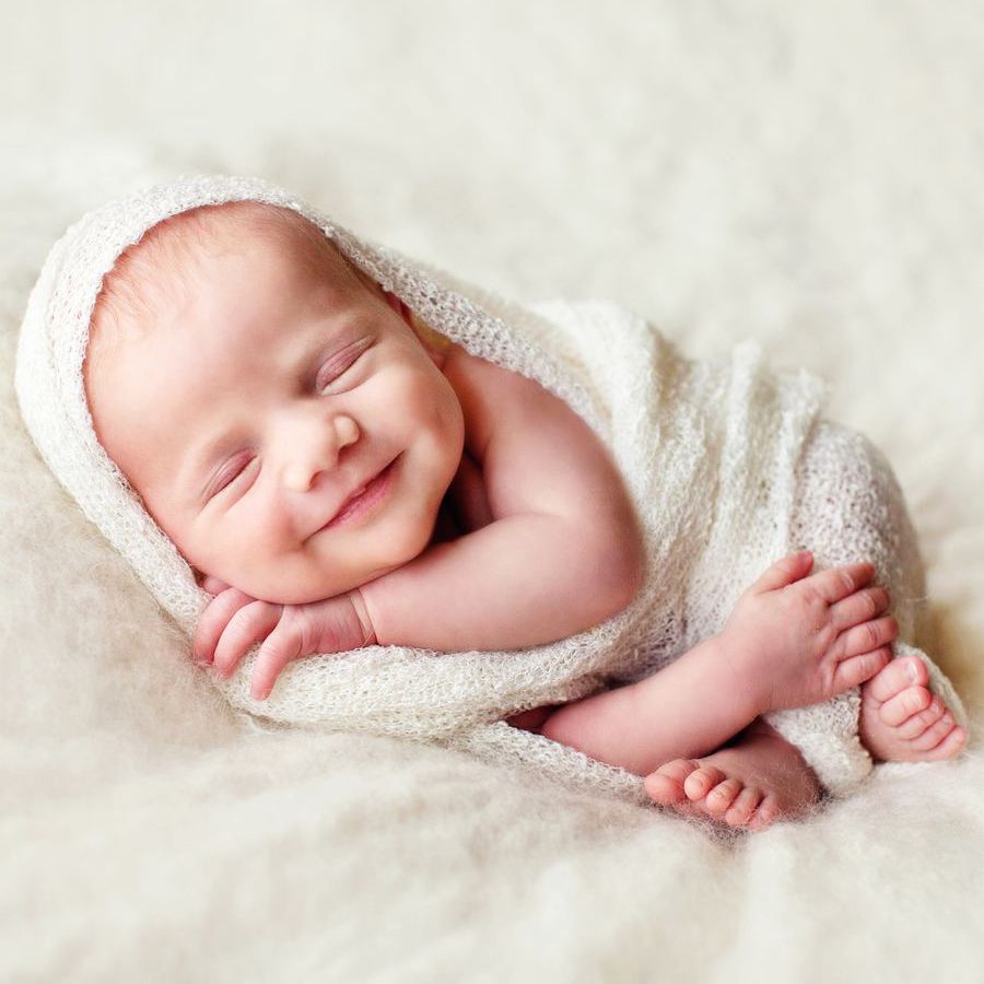 neonato sorride avvolto in coperta morbida